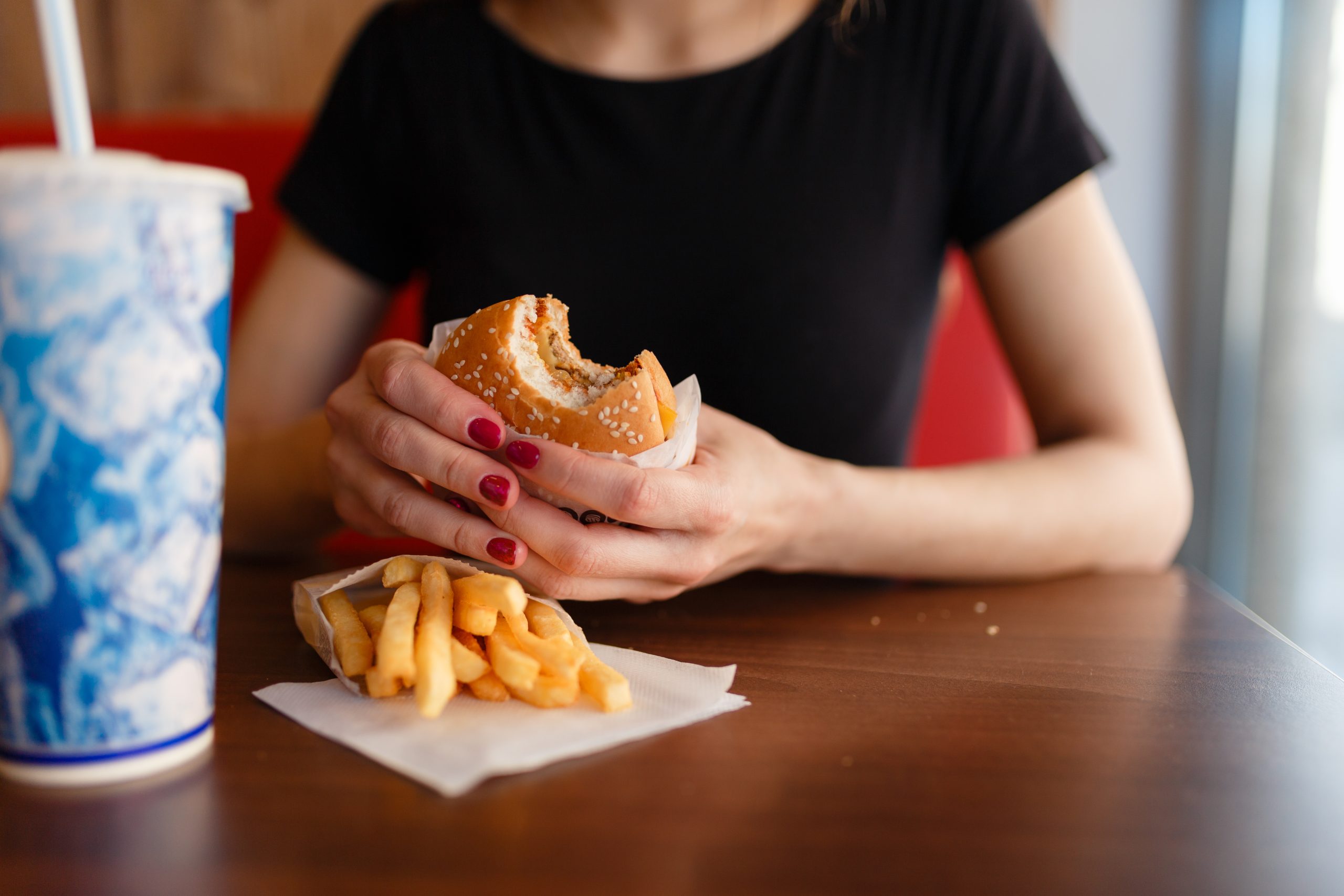 Frau isst Hamburger und Pommes